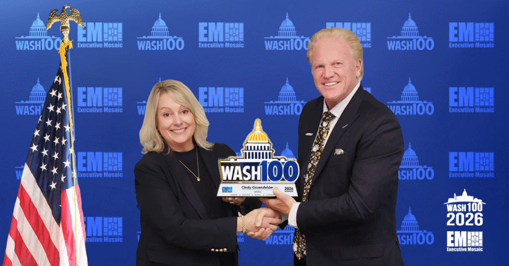 Cindy Gruensfelder and Jim Garrettson. The Leidos defense sector president shook hands with Garrettson as she accepted her first Wash100 Award.